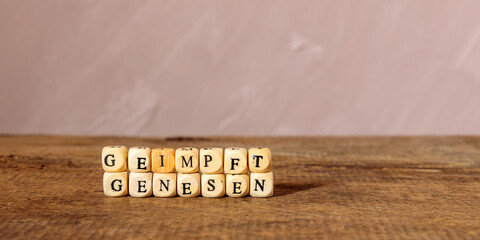 Konzept für 2G Regel: Geimpft, Genesen Schriftzug aus Holzwürfeln