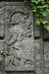 A weathered sandstone relief of a playing angel. A moss covered tombstone plate.
