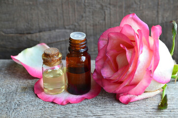 Rose essential oil in a glass bottle  on old wooden table.Spa, skin care or aromatherapy concept.Organic cosmetics.Selective focus