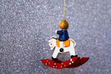 Horse-shaped Christmas tree figurine hanging from a branch on a silver background