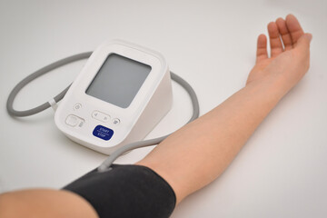 Woman measuring blood pressure with electronic digital tonometer, female hand close up. Arterial hypotension and cardiology concept.