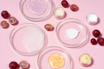 Cosmetic products, scrub, face serum and gel in many petri dishes on a pink background. Natural cosmetics from herbal ingredients.