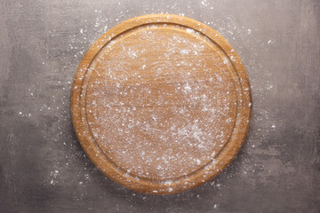 Cutting board and scattered flour powder on stone background top table. Wooden pizza board