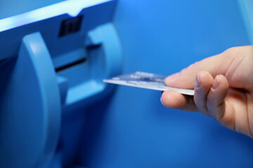 Woman inserts a bank card into ATM receiver. Financial transactions, receiving cash