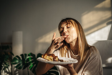Attractive girl eating croissants in a bright room. Beautiful girl eating croissants with chocolate for breakfast - obrazy, fototapety, plakaty