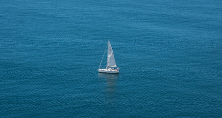 Top view of a sailboat in the peaceful blue ocean