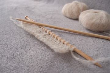 Incomplete knitting project with soft light alpaca silk yarn and bamboo knitting needles - obrazy, fototapety, plakaty