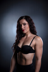 Fototapeta premium Portrait of Strong fitness woman bodybuilder with black hair and tanned body.