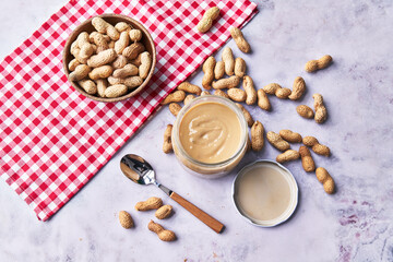  Bowl of peanuts with shell and peanut butter cream on a marble surface