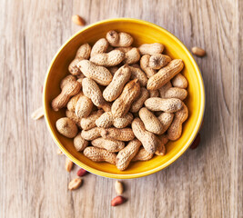  Bowl of peanuts with shell on a wooden surface