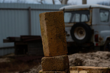 Beautiful brick, against the background of a farmyard. A brick, on a pile of bricks, in a farmer's yard, in a remote village in Russia.