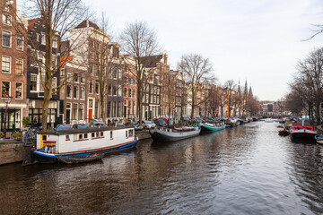 Fototapeta na wymiar Canal in the old city of Amsterdam with traditional houseboats in a winter day, Netherlands.