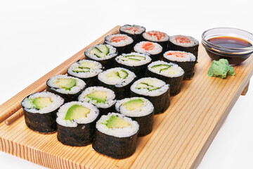  Wooden board with avocado, salmon and cucumber sushi makis isolated on white background