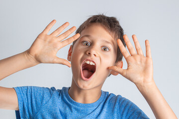 Portrait of shocked surprised boy with opening mouth and rised hands looking direct to the camera