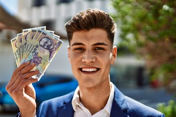 Young man wearing suit holding romania lei banknotes at street