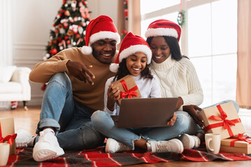 Happy festive black family using pc making videocall on Xmas