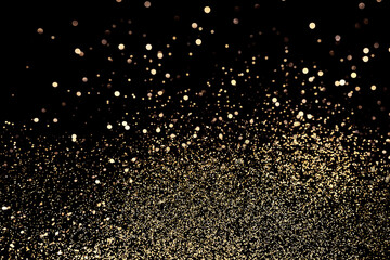 Black festive background. Abstract scattering of gold sparkles on black. Christmas backdrop, selective focus