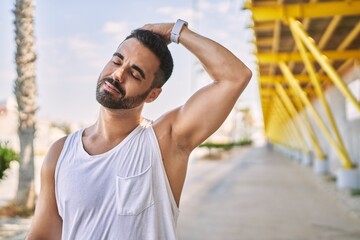 Hispanic man stretching neck after working out outdoors on a sunny day - Powered by Adobe