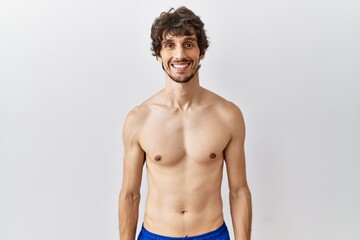Fototapeta premium Young hispanic man standing shirtless over isolated, background with a happy and cool smile on face. lucky person.