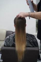 Naklejka premium Work in a hairdressing salon. High tail. Measurement with fingers by hairdresser before start.
