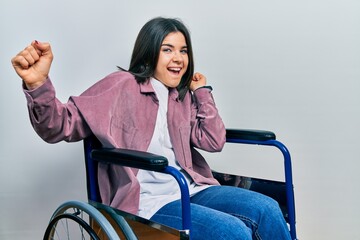 Young brunette woman sitting on wheelchair dancing happy and cheerful, smiling moving casual and confident listening to music