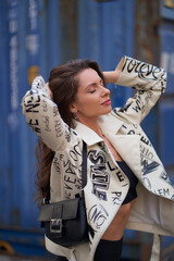 Fashion portrait of young beautiful woman in black boots, trousers, top and white leather jacket...