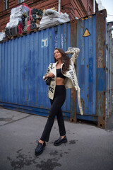 Fashion portrait of young beautiful woman in black boots, trousers, top and white leather jacket...