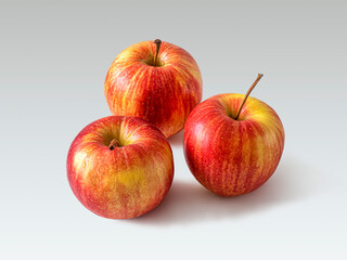 Three red-yellow apples on a light background