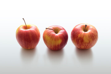 Three ripe yellow-red apples on a light background