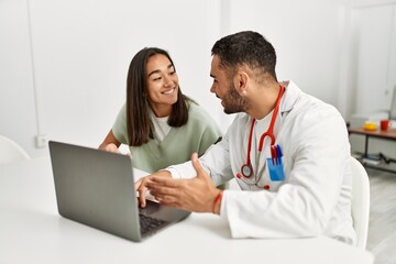 Doctor explain treatment to latin woman using laptop at clinic.