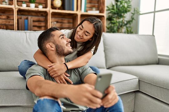 Young latin couple smiling happy making selfie by the smartphone at home.