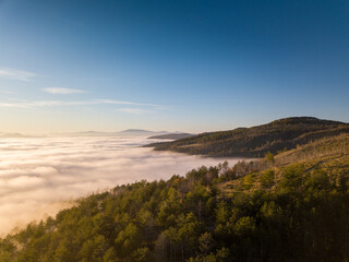 Fototapeta premium Italy November 2021: aerial view of mountains with fog below in autumn season at sunset