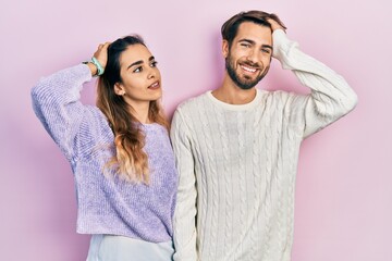 Young hispanic couple wearing casual clothes smiling confident touching hair with hand up gesture, posing attractive and fashionable