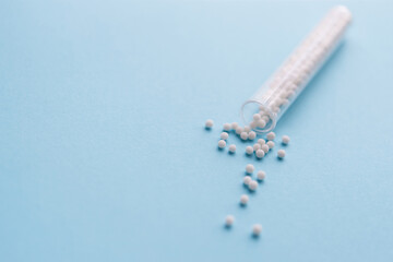 Homeopathic pills and plastic container on a blue background. Homeopathic medicine	
