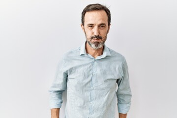 Fototapeta premium Middle age hispanic man with beard standing over isolated background puffing cheeks with funny face. mouth inflated with air, crazy expression.