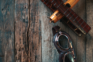 Aviation concept with toy airplane and aviator glasses on the wooden background.