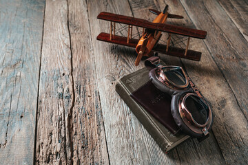 Aviation concept with toy airplane, aviator glasses, passport and flight book.