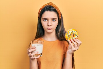 Young brunette girl eating donut and drinking glass of milk skeptic and nervous, frowning upset because of problem. negative person. - Powered by Adobe