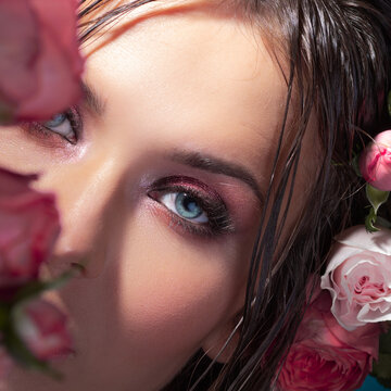A beautiful young brunette with bright blue eyes, in a Hawaiian image. Wet hair and flowers in the hairstyle