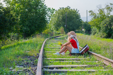 the traveler sits in a suitcase on the railroad