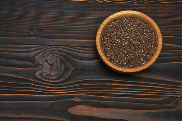 Bowl of organic natural chia seeds close-up on wooden background or table