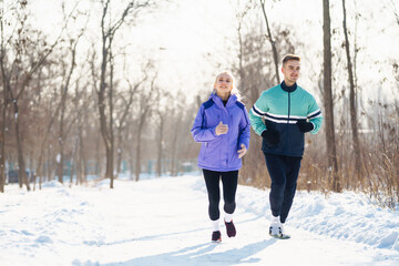 Fototapeta na wymiar Young couple winter morning exercise at snowy forest. Healthy fitness lifestyle. Sport, Active life.