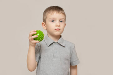 Child performs an exercise with a relief ball to develop tactile sensations. Exercise for the development of fine motor skills of the hands. Selective focus