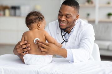 Portrait Of Handsome Black Pediatrician Examining Baby Patient With Stethoscope