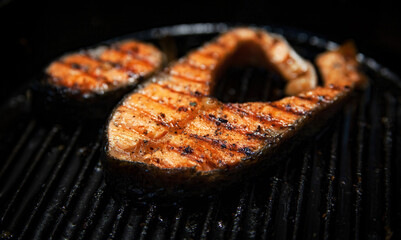 Grill red fish steak on a plate on a dark background