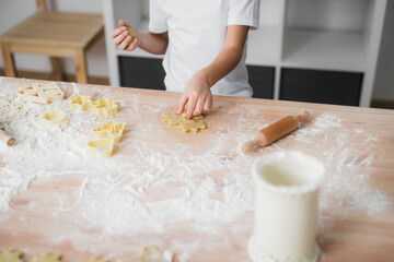 Close-up of the hands of a child who prepares cookies at home in the kitchen.