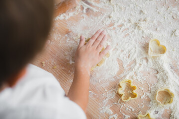 Top view, a child cuts figured cookies from dough using a culinary mold