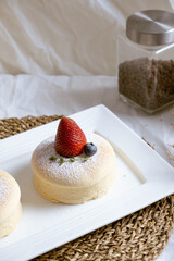 Delicious Japanese fluffy souffle pancakes on white cafe table.