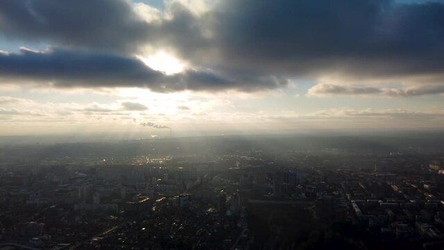 Aerial speedup footage of sun shining through epic cloudscape above misty Kharkiv city center with Park of Maxim Gorky and residential multistory buildings. Dramatic clouds with sun rays