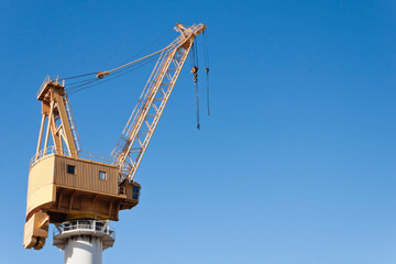 Yellow shipyard crane on blue sky background